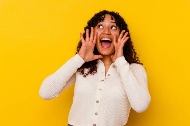 Sarı arka planda izole edilmiş genç bir ırk kadını heyecanlı bir şekilde bağırıyor..