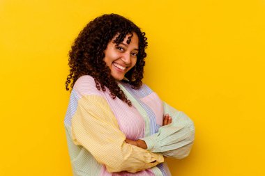 Sarı arka planda yaşayan genç melez kadın gülüyor ve eğleniyor..