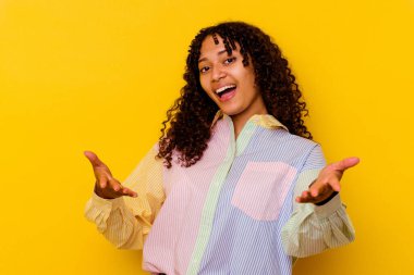 Sarı arka planda izole edilmiş genç melez kadın kameraya sarıldığı için kendinden emin..