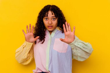 Sarı arka planda izole edilmiş genç melez bir kadın yaklaşan tehlike nedeniyle şoka uğruyor.