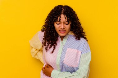 Sarı arka planda karaciğer ağrısı ve karın ağrısı çeken genç bir ırk kadını..