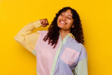 Sarı arka planda izole edilmiş genç melez kadın zaferi, tutkuyu ve coşkuyu kutluyor, mutlu bir ifade..