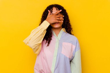 Sarı arka planda soyutlanmış genç bir ırk kadını. Gözleri ellerle kaplıyor. Gülümsüyor ve bir sürpriz bekliyor..