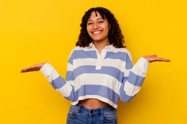 黄色の背景に隔離された若い混合人種の女性は腕でスケールを作ります 幸せと自信を感じます — ストック写真