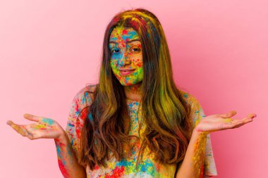 Kutsal bayramı kutlayan genç Hintli kadın beyaz arka planda izole edilmiş şüphe ve omuz silkiyor..