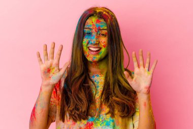 Kutsal festivali kutlayan genç Hintli kadın beyaz arka planda on numarayı elleriyle gösteriyor..