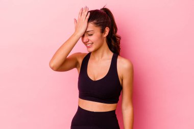 Pembe arka planda izole edilmiş genç Hintli kadın bir şeyi unutuyor. Alnına avuç içi ve kapalı gözlerle vuruyor..