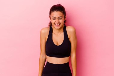 Pembe arka planda izole edilmiş genç Hintli kadın gülüyor ve gözlerini kapıyor, rahatlamış ve mutlu hissediyor..