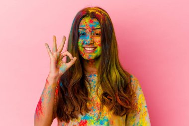 Kutsal festivali kutlayan genç Hintli kadın beyaz arka planda izole edilmiş neşeli ve kendinden emin bir şekilde iyi niyet gösteriyor..