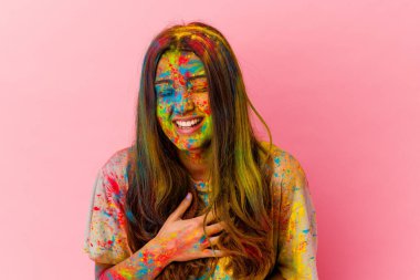 Beyaz arka planda izole edilmiş kutsal festivali kutlayan genç Hintli kadın mutlu bir şekilde gülüyor ve ellerini karnının üstünde tutarak eğleniyor..