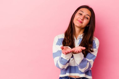 Pembe arka planda izole edilmiş genç Hintli kadın dudakları katlıyor ve hava öpücüğü göndermek için avuç içleri tutuyor..