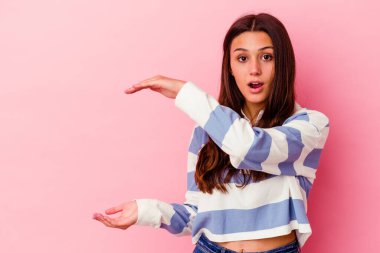 Pembe arka planda izole edilmiş genç Hintli kadın elleri arasında bir kopya alanı tutarken şok ve hayrete düştü..