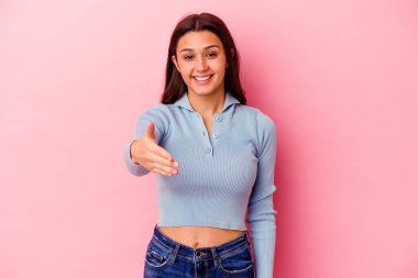 Pembe arka planda izole edilmiş genç Hintli kadın selamlama jesti olarak kameraya uzanıyor..