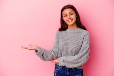 Pembe arka planda izole edilmiş genç Hintli kadın bir avuç içinin fotokopi çektiğini ve belinde başka bir el tuttuğunu gösteriyor..