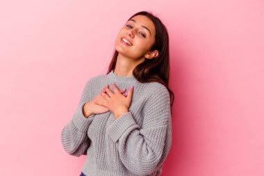 Pembe arka planda izole edilmiş genç bir Hintli kadın, dostane bir ifadeye sahip, avuçlarını göğsüne bastırıyor. Aşk konsepti.
