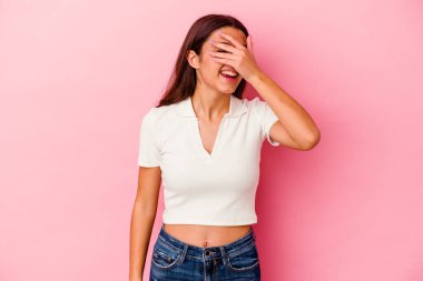 Pembe arka planda izole edilmiş genç Hintli kadın elleriyle gözlerini kapatıyor, geniş bir gülümsemeyle bir sürpriz bekliyor..