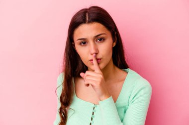Pembe arka planda izole edilmiş genç Hintli bir kadın ya sır saklıyor ya da sessizlik istiyor..