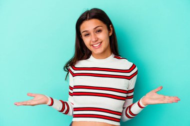 Mavi arka planda izole edilmiş genç Hintli kadın hoş bir ifade sergiliyor..