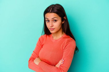 Mavi arka planda izole edilmiş genç Hintli kadın şüpheli, belirsiz, seni muayene ediyor..