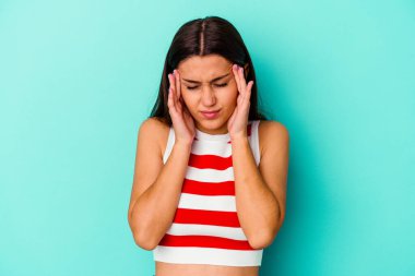 Genç Hintli kadın mavi arka planda izole edilmiş tapınaklara dokunuyor ve baş ağrısı çekiyor..