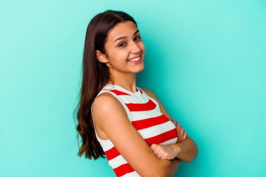 Mavi arka planda izole edilmiş genç Hintli kadın mutlu, güler yüzlü ve neşeli.