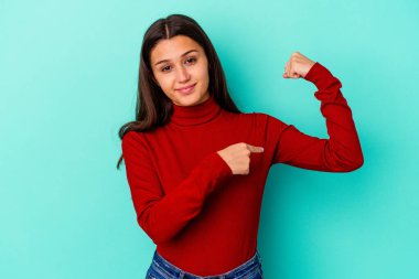 Mavi arka planda izole edilmiş genç bir Hintli kadın güçlü bir hareket sergiliyor. Kadınsı gücün sembolü.