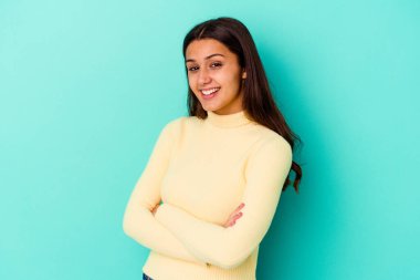 Genç Hintli kadın mavi arka planda izole edilmiş gülüyor ve eğleniyor.