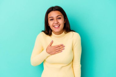 Mavi arka planda izole edilmiş genç Hintli kadın kahkahalar atıyor..