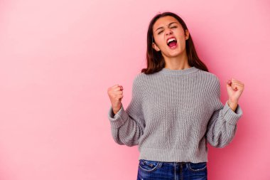 Pembe arka planda izole edilmiş genç Hintli kadın zaferden sonra yumruğunu kaldırıyor, kazanan konsept..