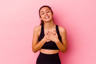 Genç sporcu Hintli kadın pembe arka planda izole halde gülüyor ellerini kalbe koyuyor, mutluluk kavramını koruyor..
