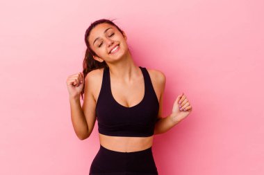 Genç Hintli kadın pembe arka planda izole edilmiş dans ediyor ve eğleniyor..