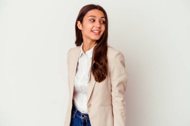 Beyaz arka planda soyutlanmış genç Hintli iş kadını gülümseyen, neşeli ve keyifli bir kenara bakıyor..