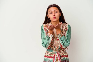 Beyaz arka planda izole edilmiş genç Hintli bir kadın. Dudaklarını kıvırıyor, avuç içlerini tutuyor ve hava öpücüğü yolluyor..