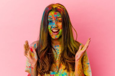 Kutsal bayramı kutlayan genç Hintli kadın beyaz arka planda izole edilmiş bir şekilde zaferi veya başarıyı kutluyor, şaşırıyor ve şok oluyor..