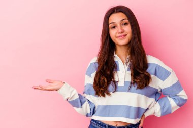 Pembe arka planda izole edilmiş genç Hintli kadın bir avuç içinin fotokopi çektiğini ve belinde başka bir el tuttuğunu gösteriyor..