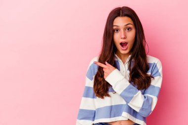 Pembe arka planda izole edilmiş genç Hintli kadın yan tarafı gösteriyor.