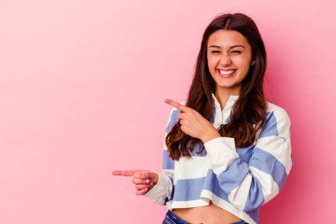 Pembe arka planda izole edilmiş genç Hintli kadın işaret parmaklarıyla fotokopi alanını işaret ederek heyecan ve arzusunu ifade ediyor..