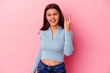 Pembe arka planda izole edilmiş genç Hintli kadın parmaklarıyla taş hareketi gösteriyor.