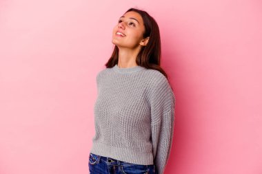 Genç Hintli kadın pembe arka planda izole edilmiş rahat ve mutlu bir şekilde gülüyor, boynunda dişlerini gösteriyor..