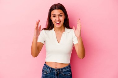 Pembe arka planda izole edilmiş genç Hintli kadın hoş bir sürpriz alıyor, heyecanlı ve el kaldırıyor..