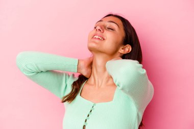 Pembe arka planda soyutlanmış genç Hintli bir kadın kendini güvende hissediyor, elleri başının arkasında..