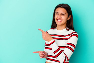 Mavi arka planda izole edilmiş genç Hintli kadın işaret parmaklarıyla fotokopi alanını işaret ederek heyecan ve arzusunu ifade ediyor..