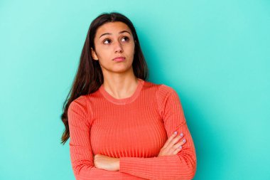 Mavi arka planda izole edilmiş genç Hintli kadın tekrarlanan bir görevden yoruldu.