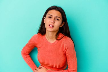 Mavi arka planda izole edilmiş genç bir Hintli kadın. Karaciğer ağrısı, mide ağrısı var..