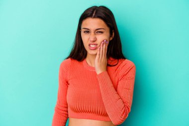 Mavi arka planda izole edilmiş genç bir Hintli kadın. Güçlü bir diş ağrısı, azı dişi ağrısı var..