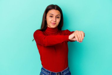 Genç Hintli kadın mavi arka planda izole kollarını uzatarak, rahat bir konumda..