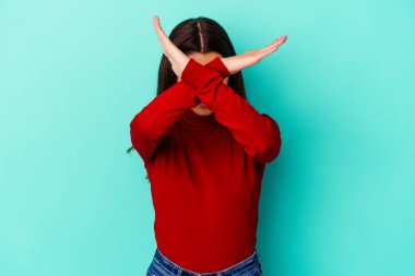 Genç Hintli kadın mavi arka planda izole edilmiş iki kolu çapraz tutuyor, inkar kavramı.