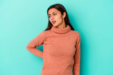 Genç Hintli kadın mavi arka planda izole edilmiş sırt ağrısı çekiyor..