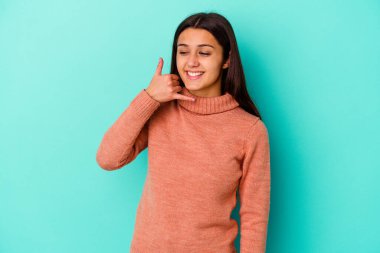 Mavi arka planda izole edilmiş genç Hintli kadın parmakları olan bir cep telefonu hareketi gösteriyor..