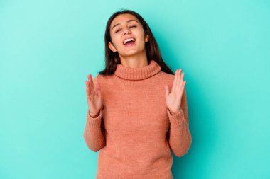 Mavi arka planda izole edilmiş genç Hintli kadın kahkahalar atıyor..